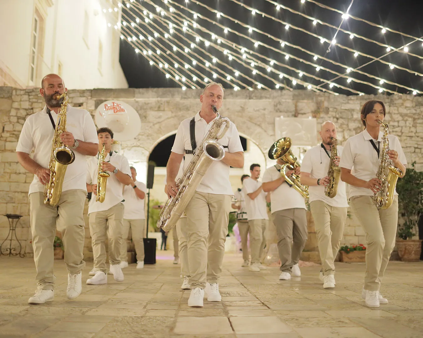 Band di sassofonisti che sfila sotto le luci in una location all'aperto